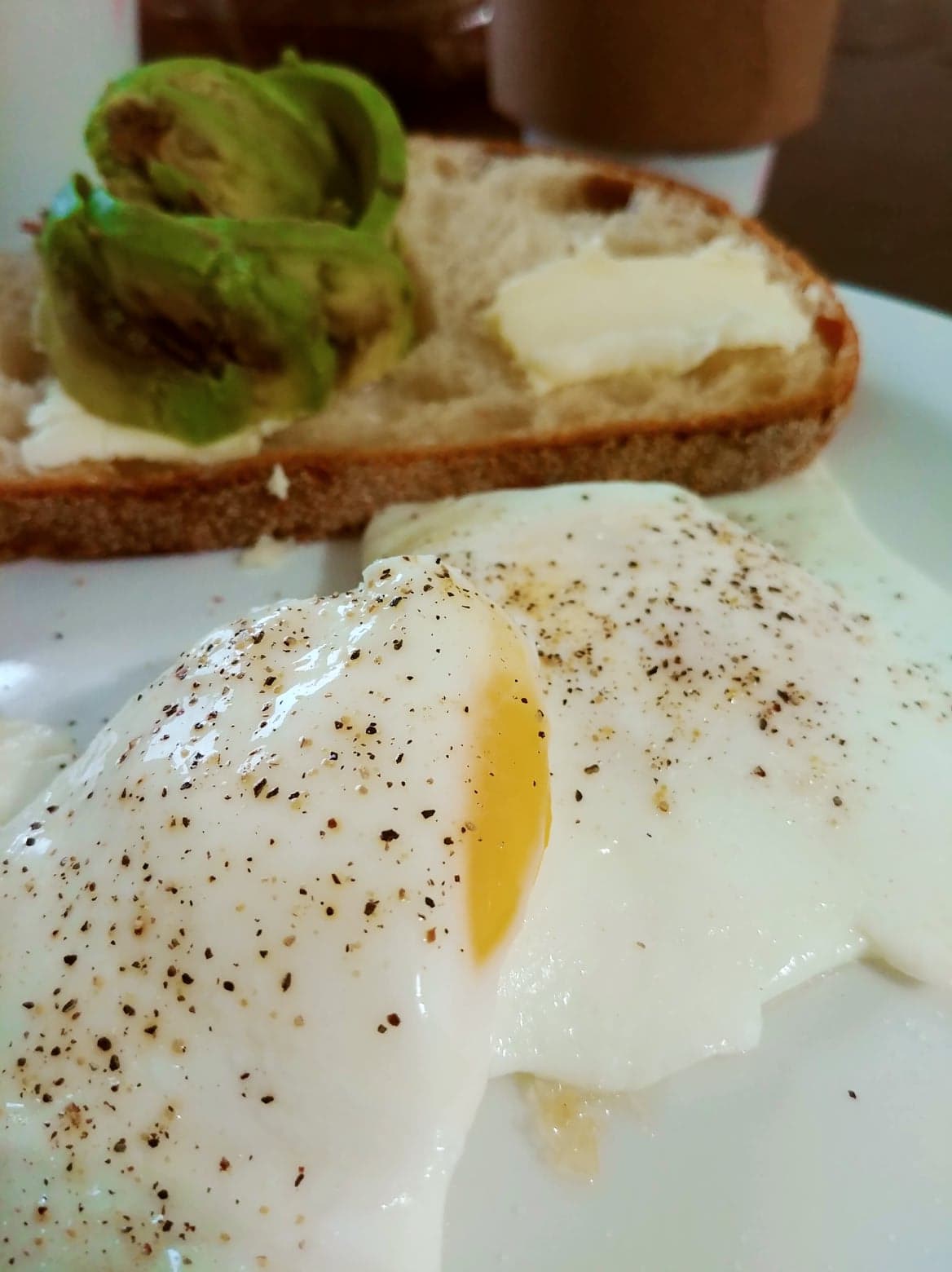 Close up of seasoned over easy eggs with avocado toast in background